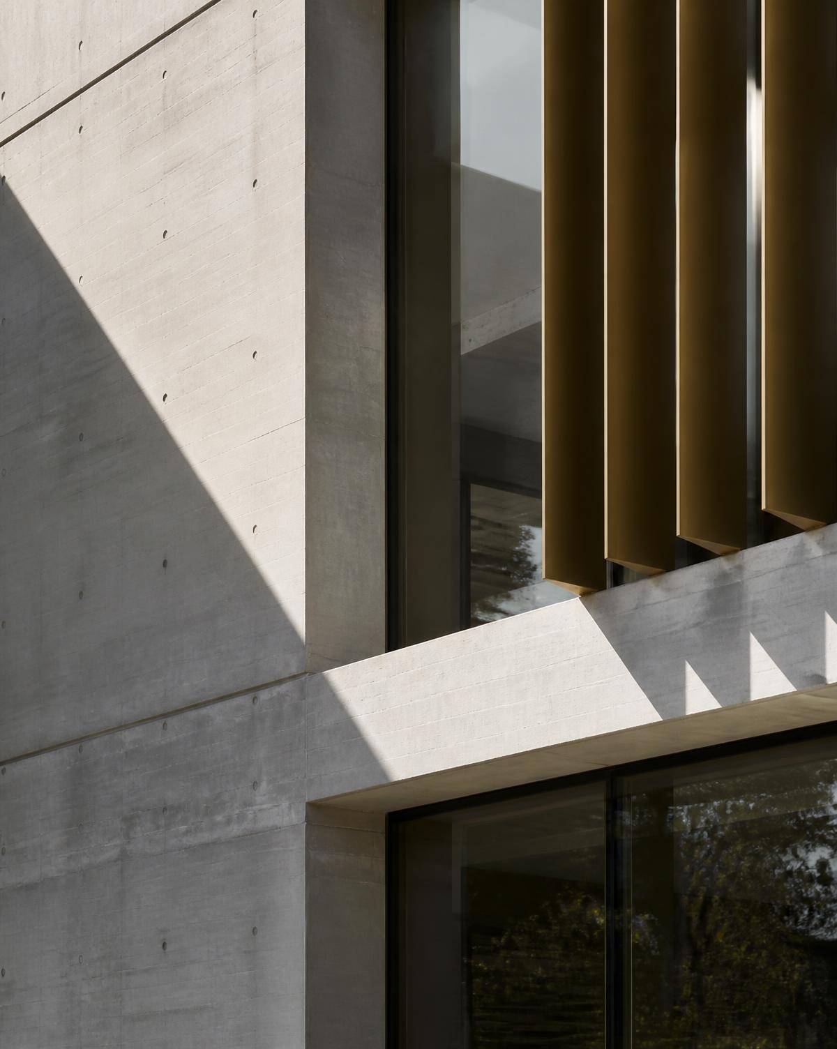 Detalhe arquitetônico em concreto aparente e elementos verticais em bronze